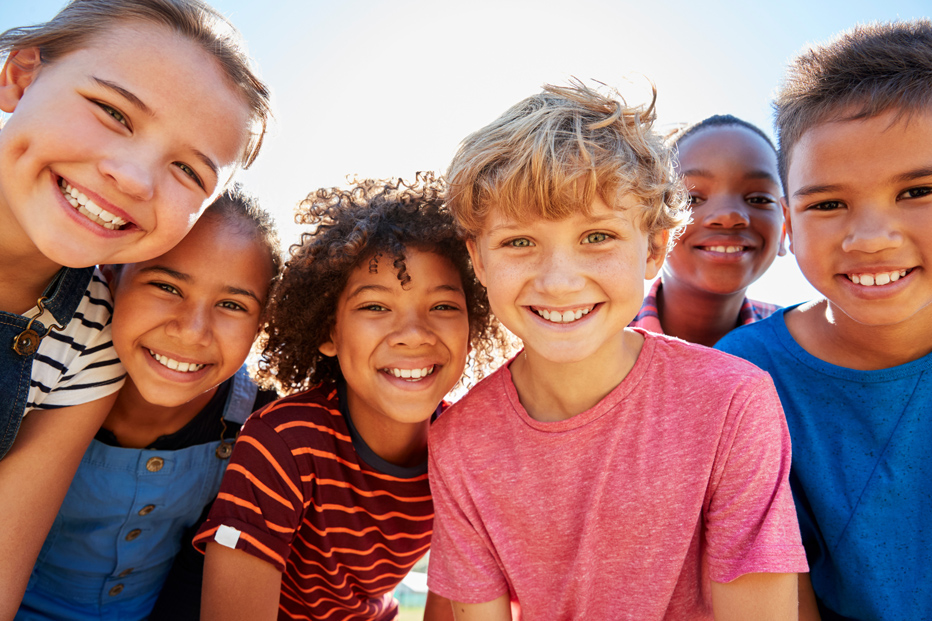 Close up photo of pre-teen friends in a park smiling to camera