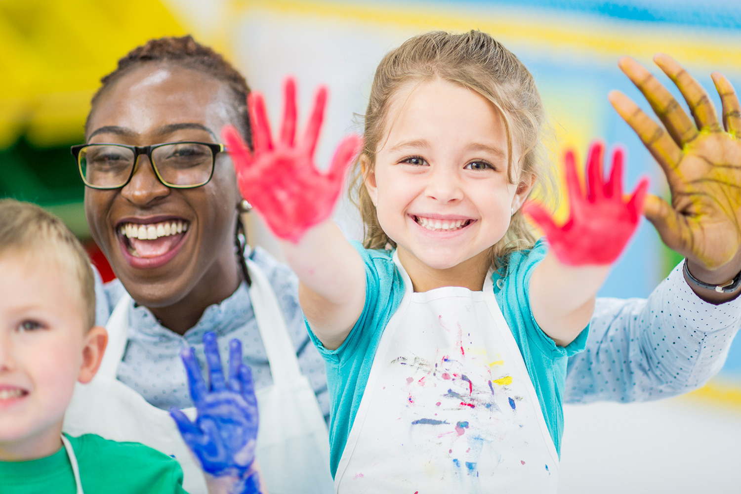 Children and adult showing painty hands smile at camera